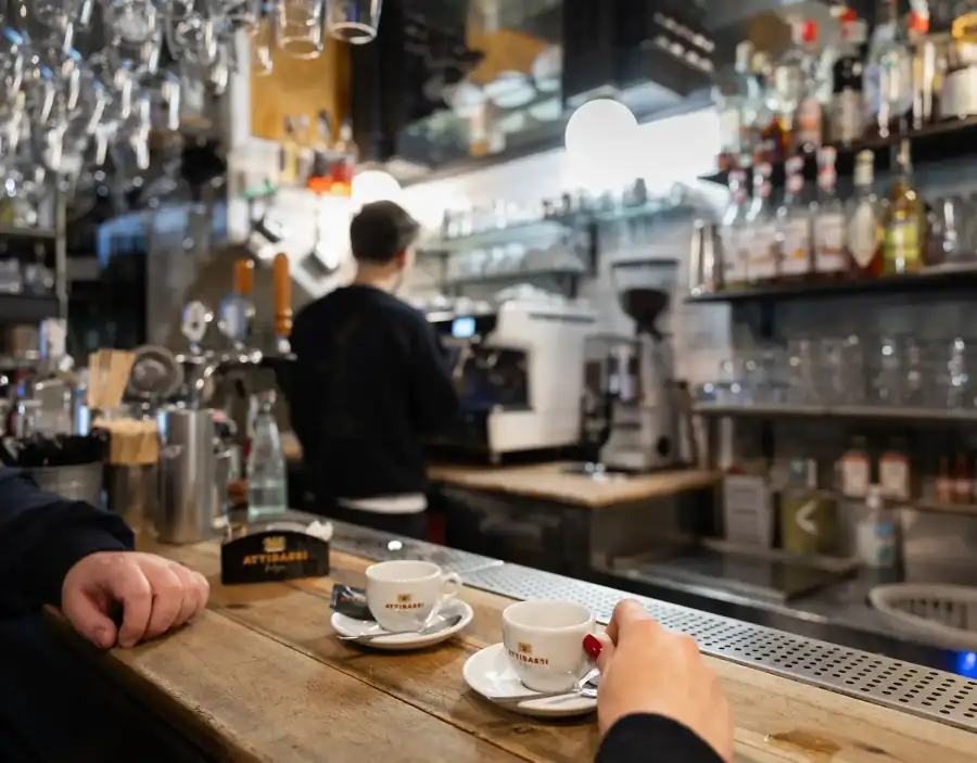 Due persone prendono il caffè Attibassi al bancone del bar