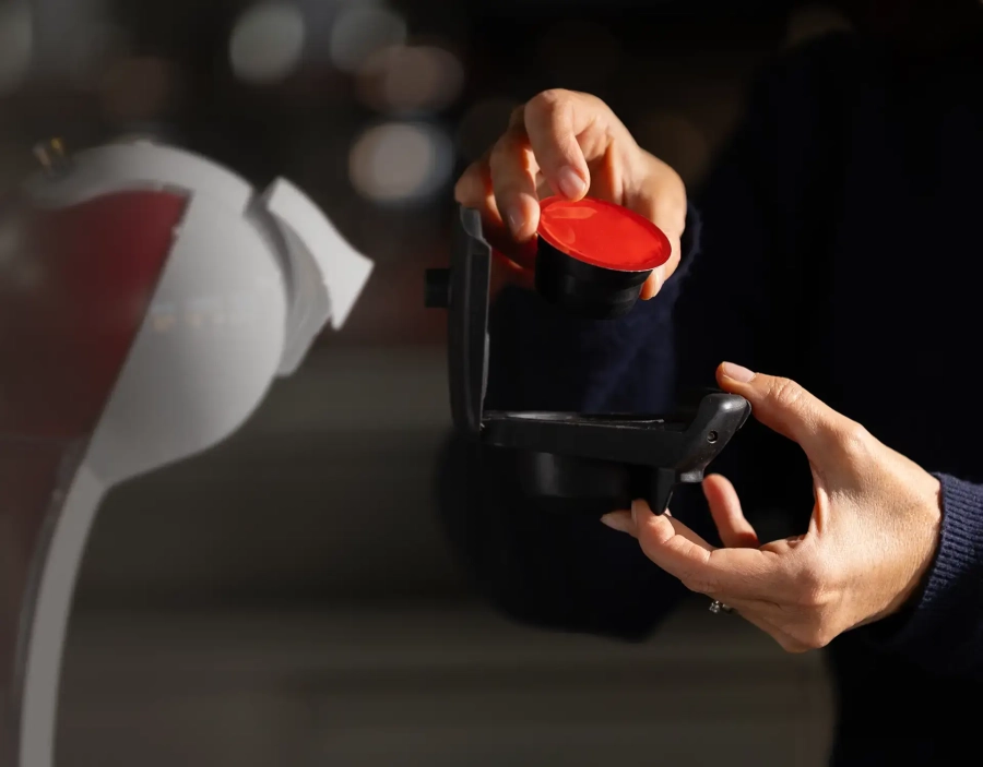 Persona inserisce una capsula compatibile Dolce Gusto nel supporto della macchina del caffè